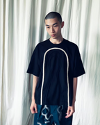 CALCÈLの黒い綿100%天竺Tシャツ。フロントにコード糸でお地蔵さんのシルエットが描かれたゆったりとしたデザイン。