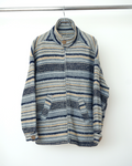 CALCÈLのスタンドカラージップジャケット。グレー、淡い黄、濃紺の幾何学的な横縞模様が特徴で、木目調のボタンとジッパーを備えた厚手の織地。