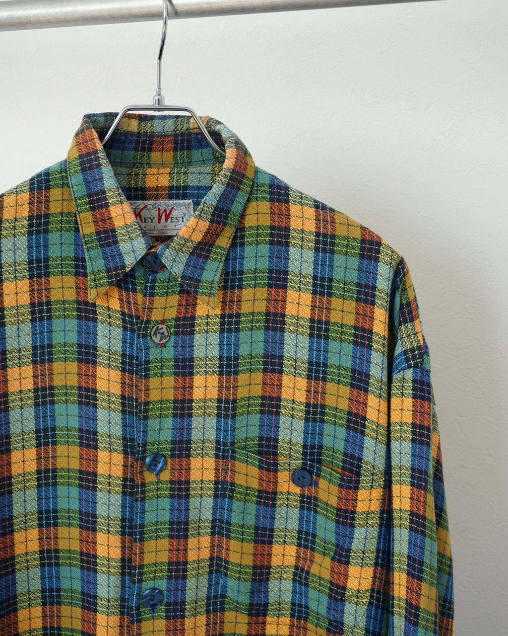 CALCÈLのKey West Shirts製、オレンジや青の多色チェック柄長袖シャツ。織り感のある生地と特徴的なボタンが魅力。