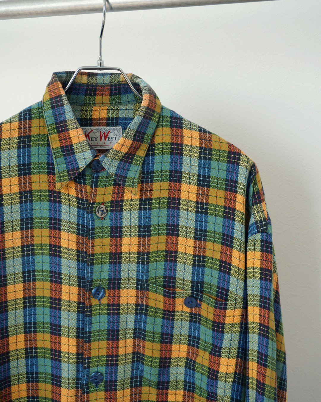 CALCÈLのKey West Shirts製、オレンジや青の多色チェック柄長袖シャツ。織り感のある生地と特徴的なボタンが魅力。