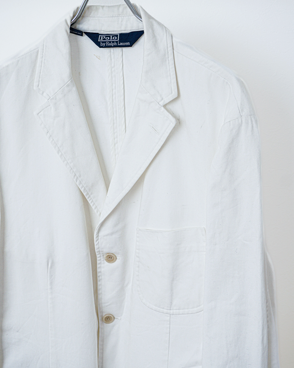 CALCÈLのPolo by Ralph Laurenオフホワイトの3つボタンシングルジャケット。斜め畝のある生地とノッチドラペルが特徴的なゆったりとしたシルエット。