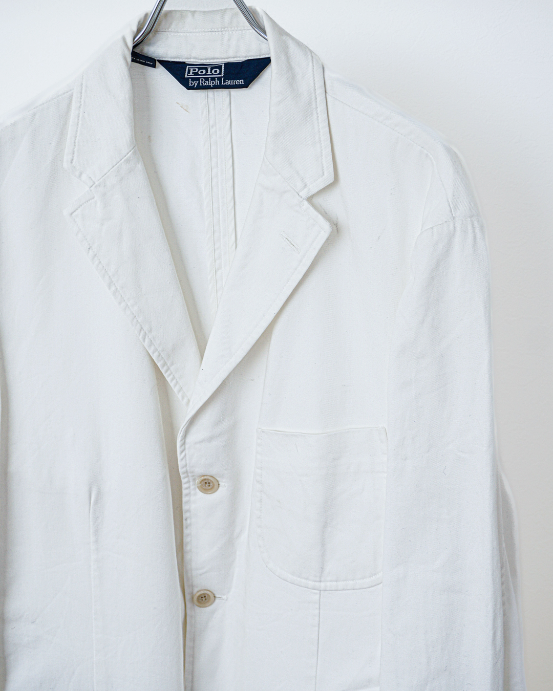 CALCÈLのPolo by Ralph Laurenオフホワイトの3つボタンシングルジャケット。斜め畝のある生地とノッチドラペルが特徴的なゆったりとしたシルエット。