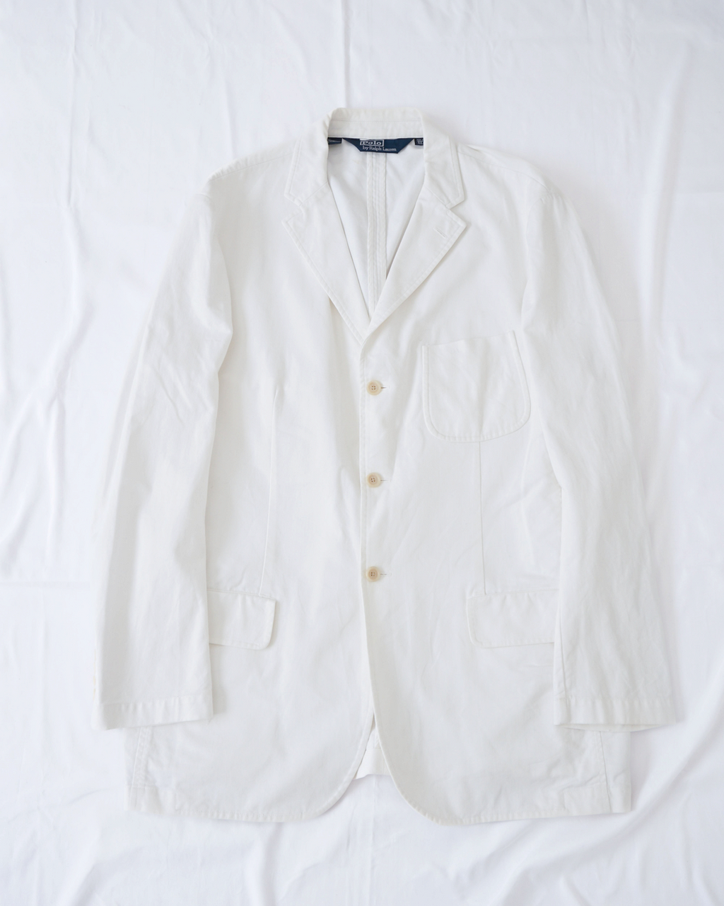 CALCÈLのPolo by Ralph Laurenオフホワイトの3つボタンシングルジャケット。斜め畝生地でノッチドラペルとパッチポケット付きのゆったりとしたシルエット。