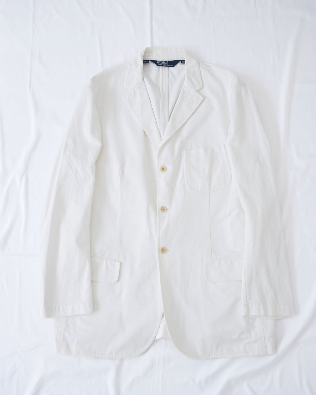 CALCÈLのPolo by Ralph Laurenオフホワイトの3つボタンシングルジャケット。斜め畝生地でノッチドラペルとパッチポケット付きのゆったりとしたシルエット。