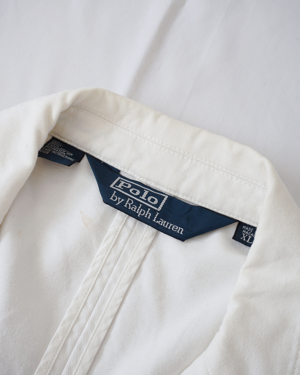 CALCÈLで取り扱うPolo by Ralph Laurenのオフホワイトのジャケット。襟裏にタグと薄い汚れが見えるクローズアップ。