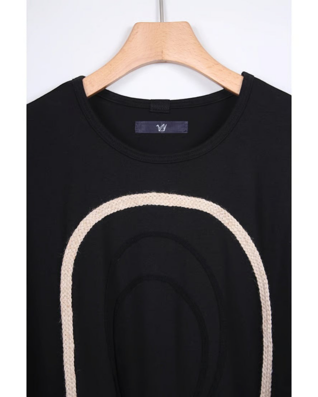 CALCÈLの黒い綿100%天竺Tシャツ。フロントにコード糸で描かれたお地蔵さんのシルエットが特徴的なゆったりとしたデザイン。