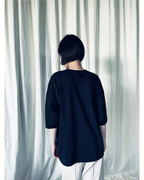 CALCÈLのohta 26ss黒い綿100%天竺Tシャツを着用したモデルの後ろ姿