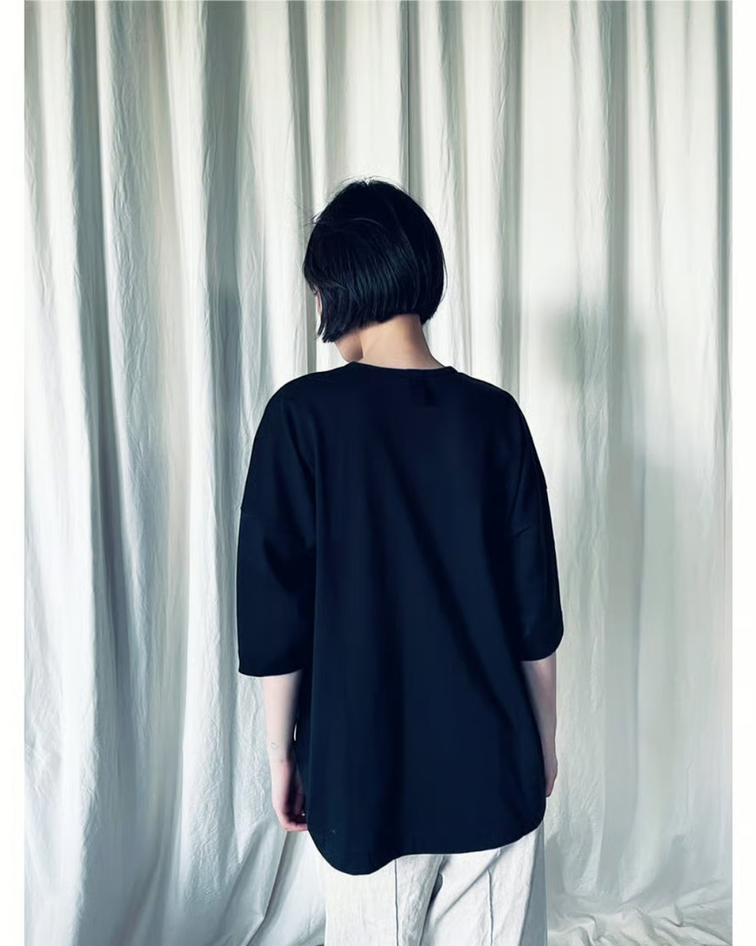 CALCÈLのohta 26ss黒い綿100%天竺Tシャツを着用したモデルの後ろ姿